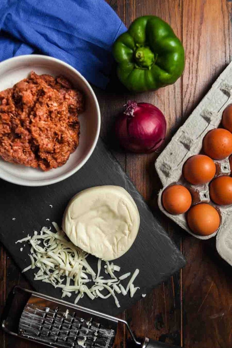 An overhead view of ingredients needed to make a Mexican chorizo omelette: Mexican chorizo, bell pepper, red onion, eggs, cheese.