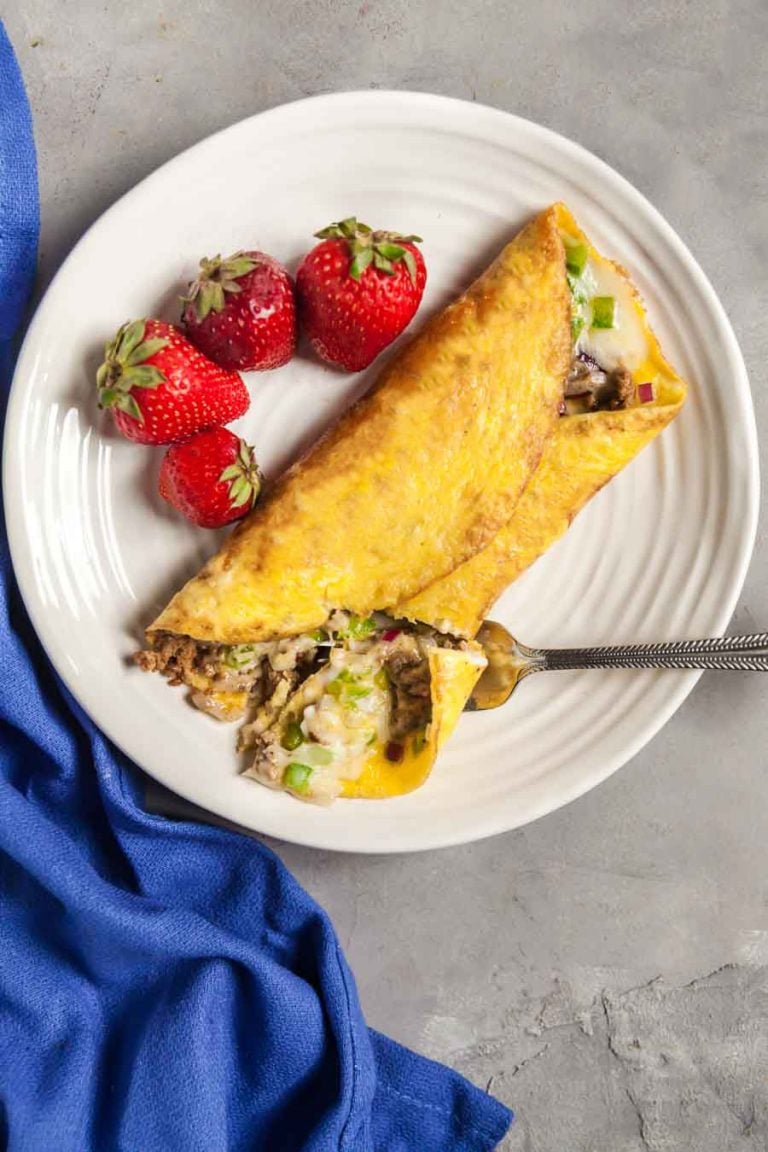 An overhead view of a chorizo omlette on a white plate with a blue napkin. 