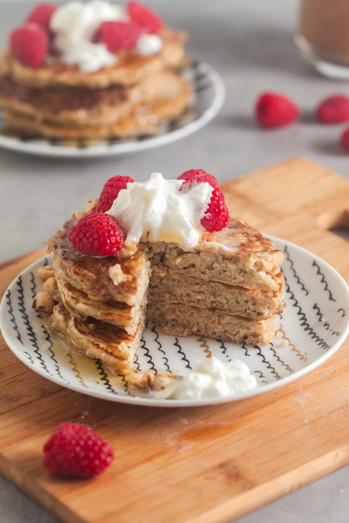 A stack of oatmeal pancakes topped with berries and whipped cream. 