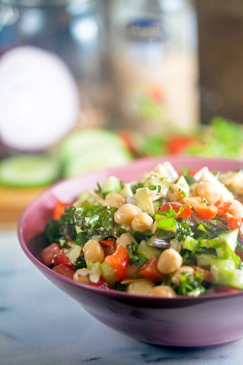 Crunchy kale and chickpea salad in a pink bowl. 