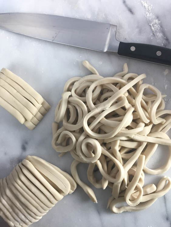 Cutting udon noodles into strips. 