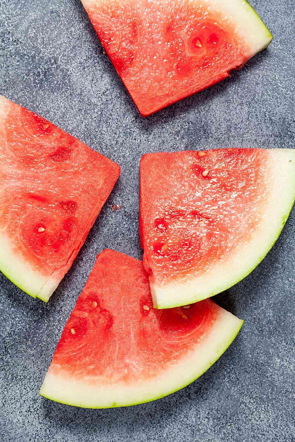 Overhead view of sliced watermelon on a speckled background. 