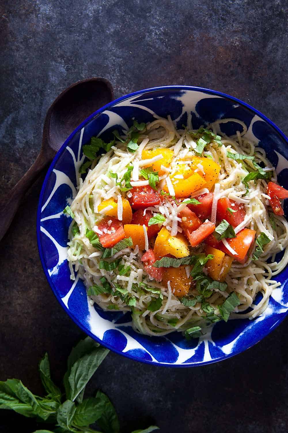 A bowl of caprese pasta with fresh tomatoes, basil, and mozzarella cream sauce