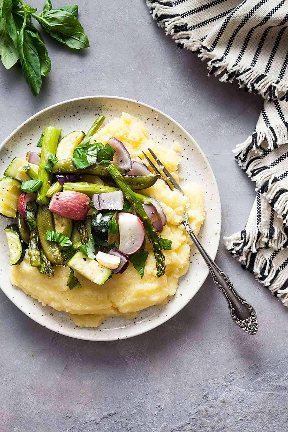 Roasted spring vegetables over a plate of soft polenta. 