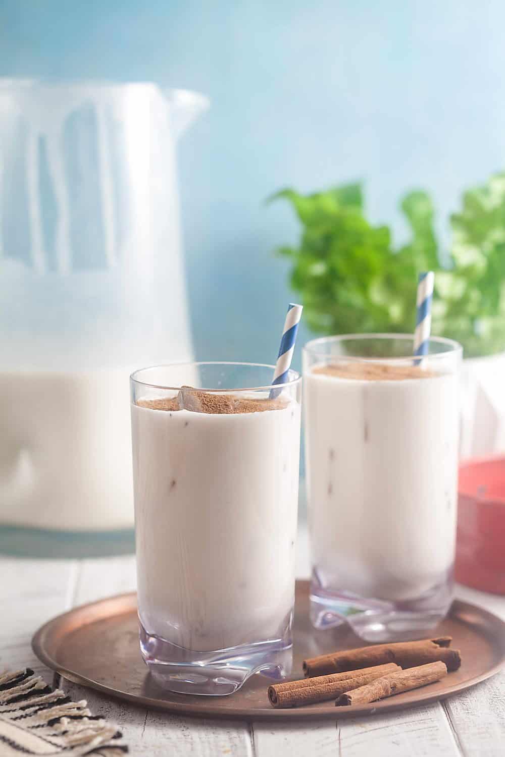 Two glasses of dairy free horchata on a platter with a pitcher in the background