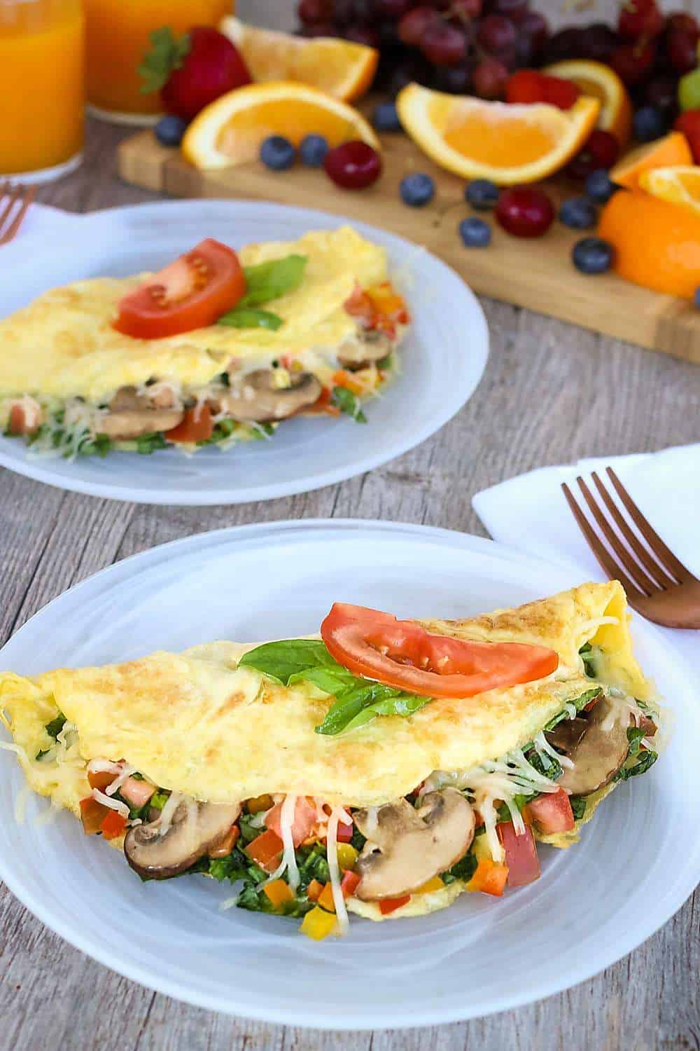 Overhead view of omelets with spinach on a gray plate with fresh berries and orange juice.