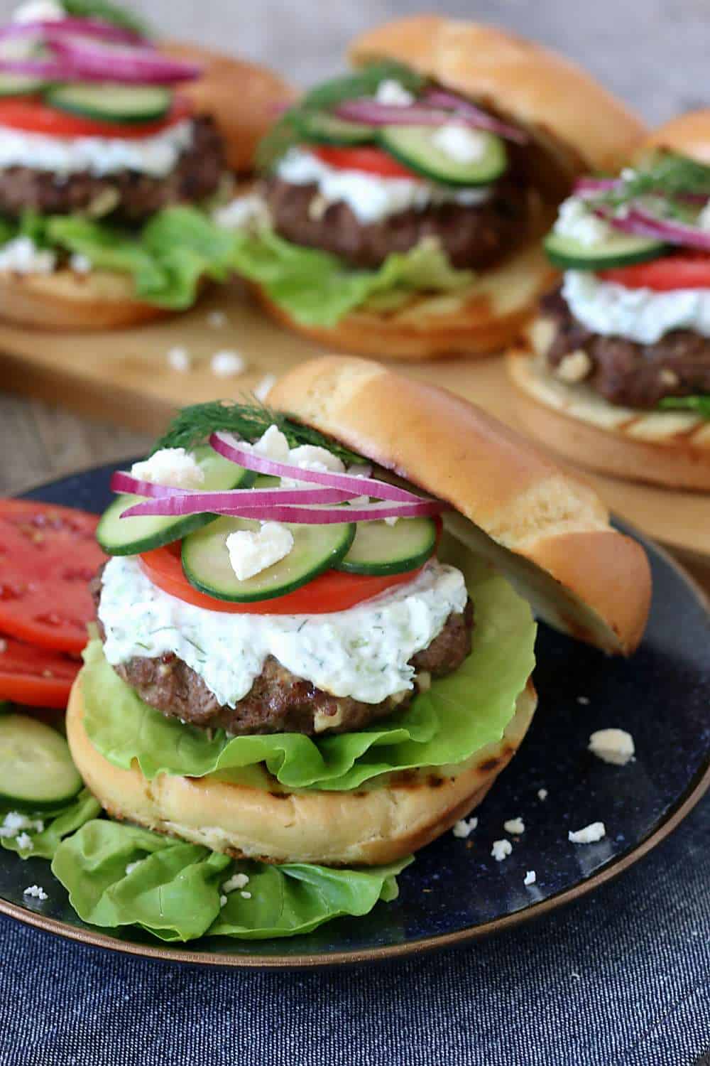 Homemade burgers with feta cheese on a bun with veggies on a plate ready to eat. 