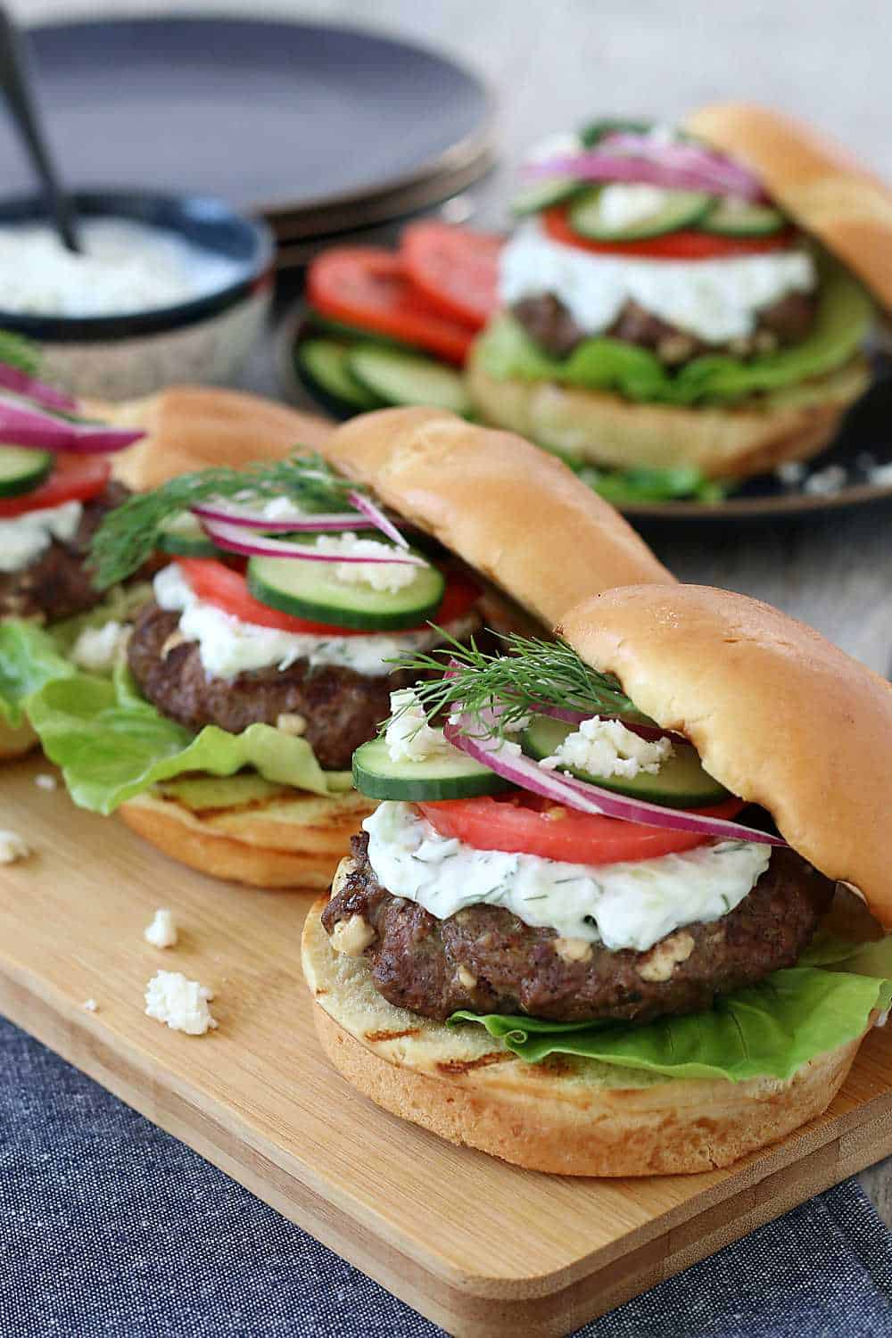 Feta cheese burgers on a wooden cutting board ready to be eaten. This Greek burger recipe looks excellent when finished!