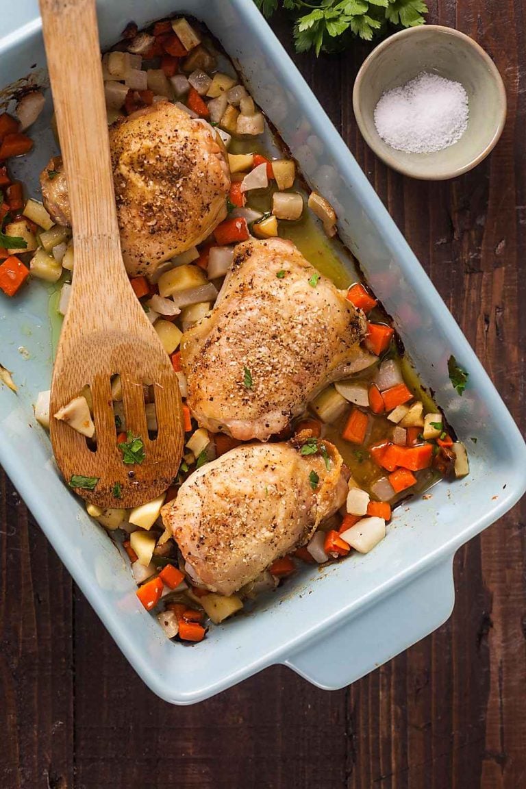 A dish full of crispy chicken thighs with carrots, parsnip, and turnip