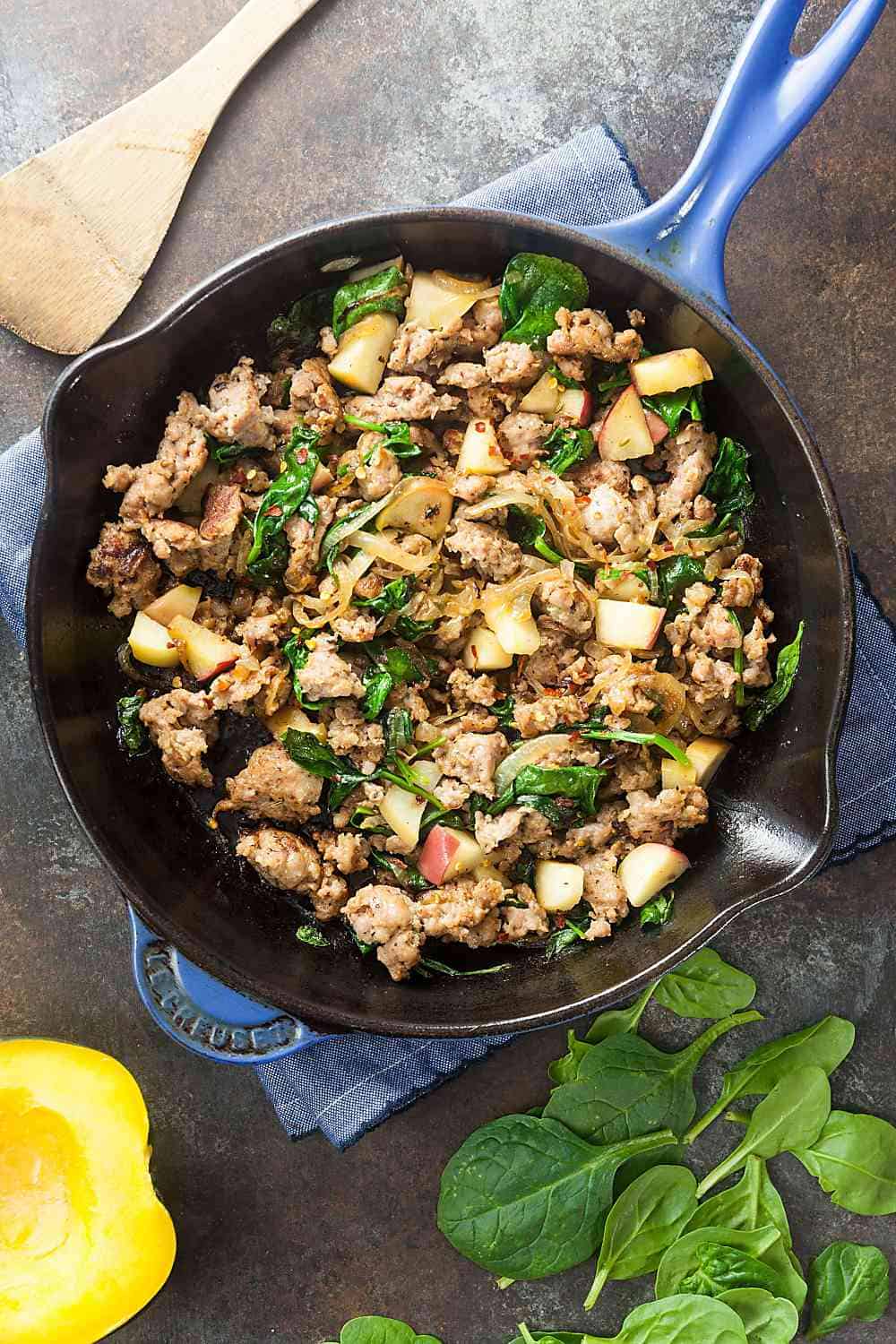 The filling for sausage stuffed acorn squash is made with sausage, spinach, apples, and caramelized onions