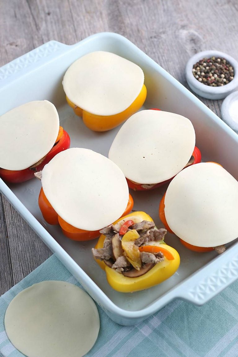 The slices of provolone are added on top of the keto stuffed peppers before they go into the oven.
