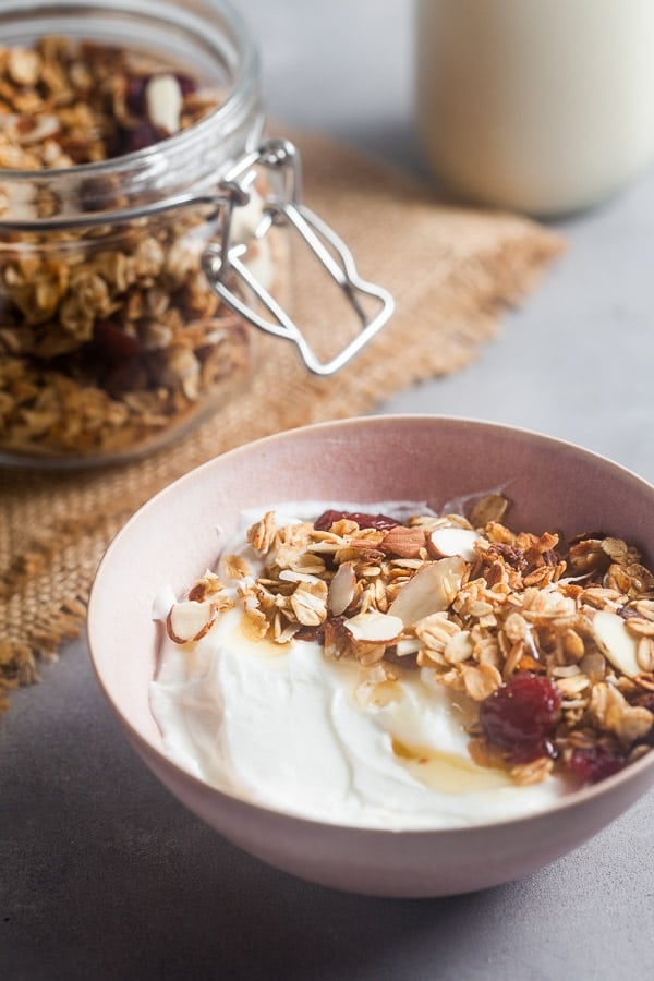 A bowl of yogurt topped with homemade granola and honey