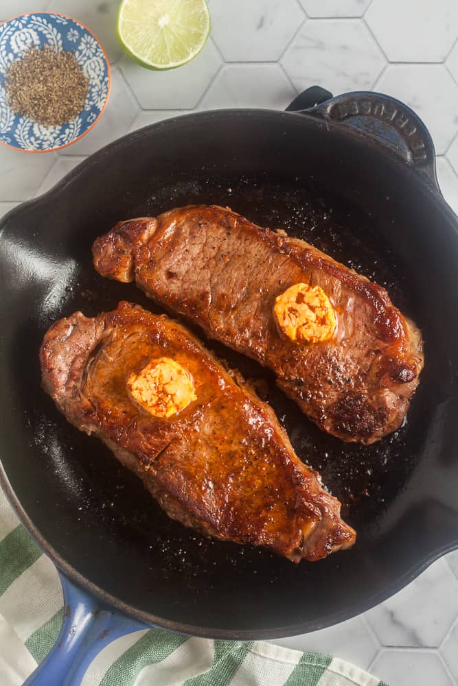 overhead view of two steaks with butter in a pan