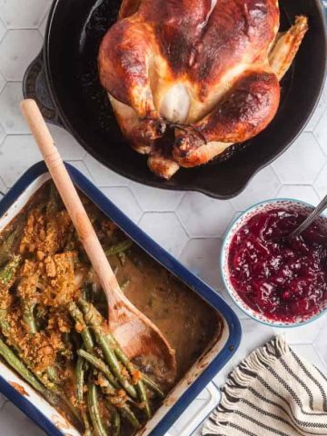 overhead view of chicken dinner with roast chicken, cranberry sauce, and fresh green bean casserole