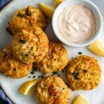 overhead view of crab cakes and remoulade sauce on a white platter.