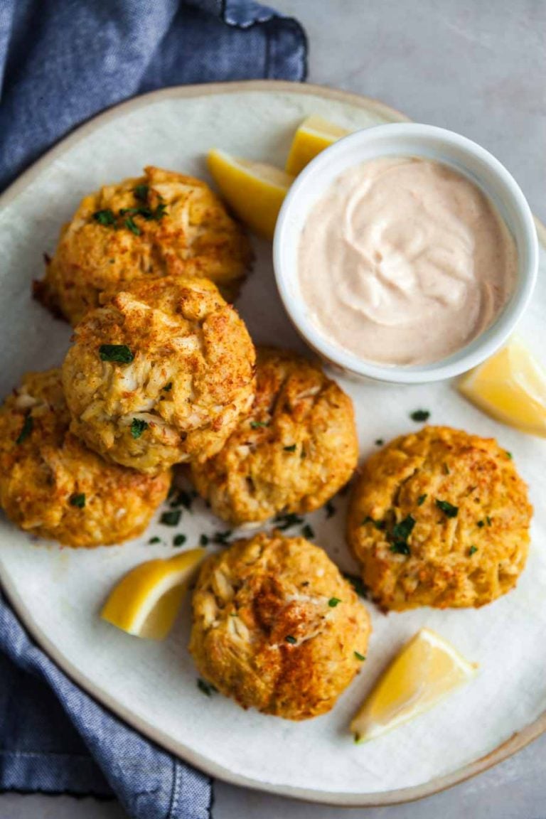 overhead view of crab cakes and remoulade sauce on a white platter. 