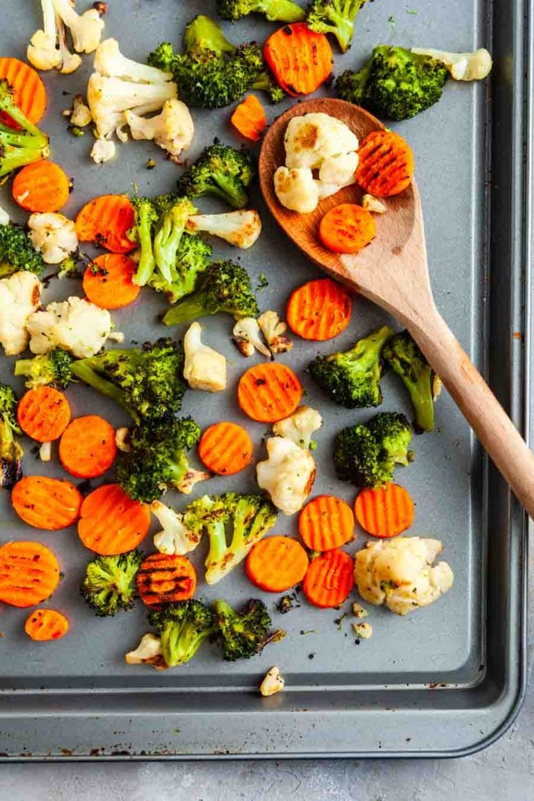 An overhead view of frozen mixed vegetables (carrots, cauliflower, and broccoli) on a sheet pan. 
