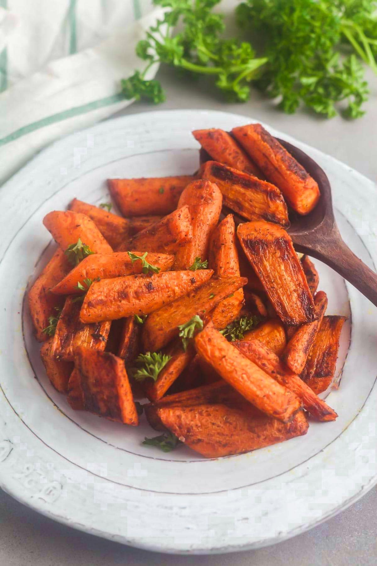 A serving bowl of roasted carrots with Moroccan spices and fresh parsley. 