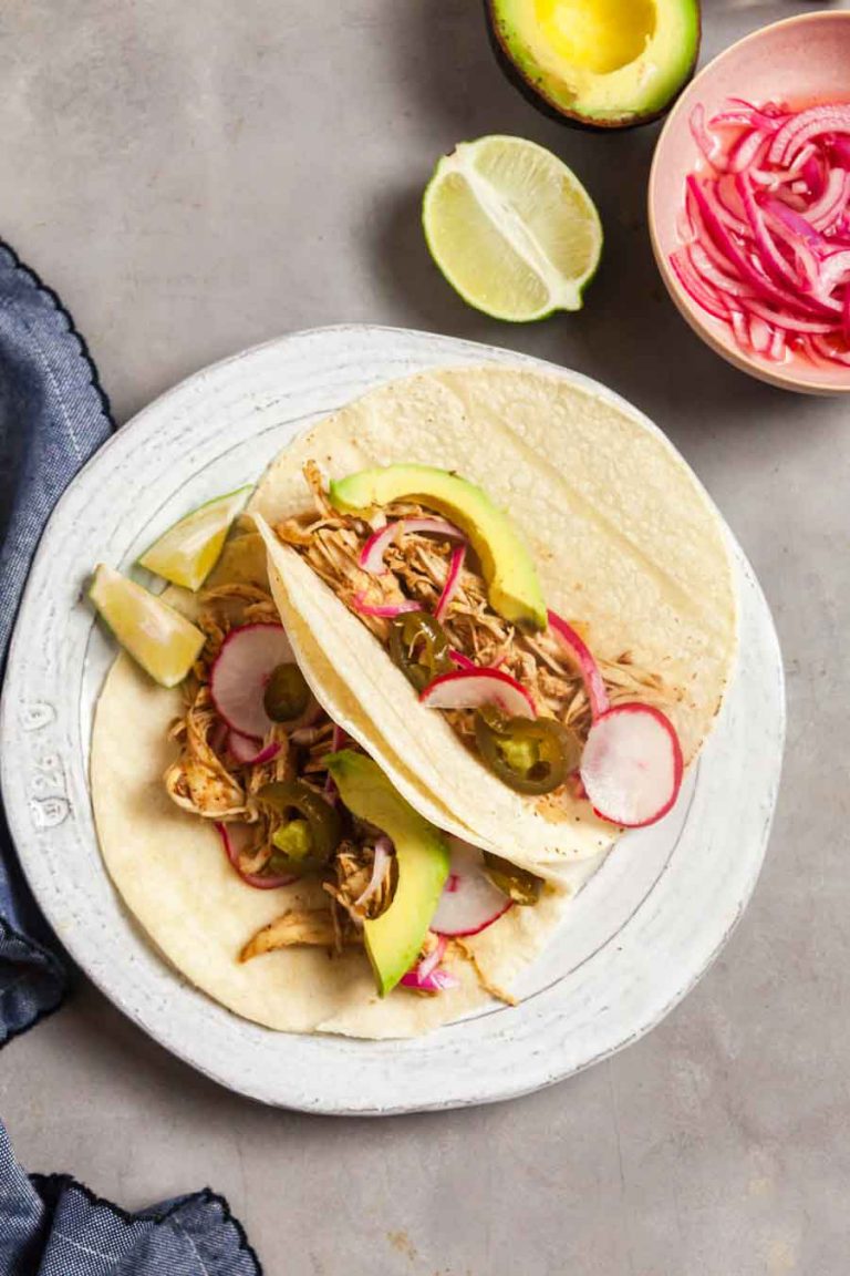 An overhead view of chicken carnitas tacos made in the Instant Pot! These tacos are topped with radishes, avocado, and pickled onion. 