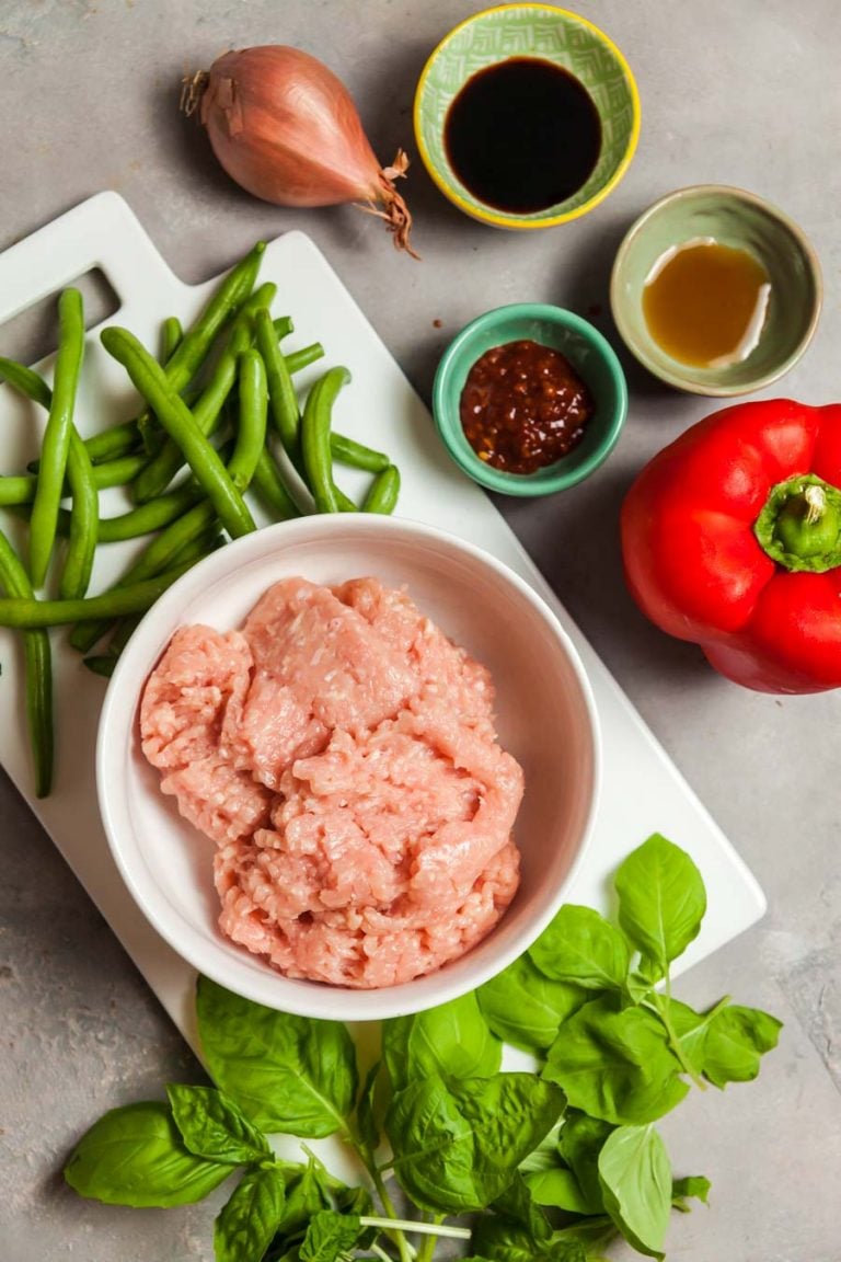 Overhead view of ingredients to makeThai basil chicken on a light grey background. 