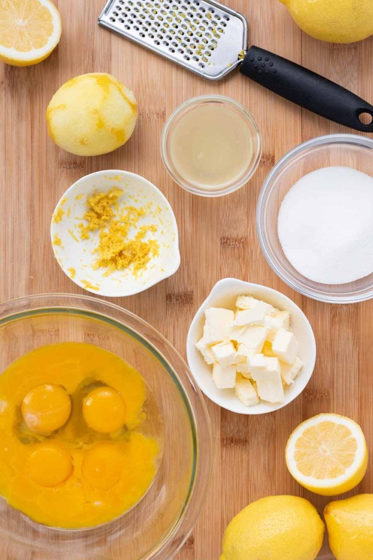 Overhead view of ingredients for making lemon curd on a wooden cutting board. 