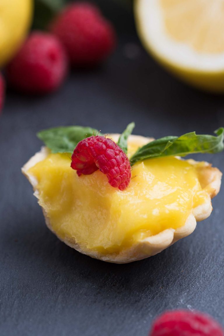 Close up view of a min lemon tartlet with a bite taken out. 