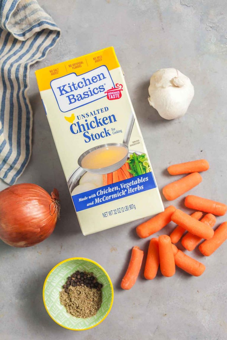 Overhead view of the ingredients needed to make homemade chicken gravy: chicken stock, onion, carrots, garlic, and seasonings. 