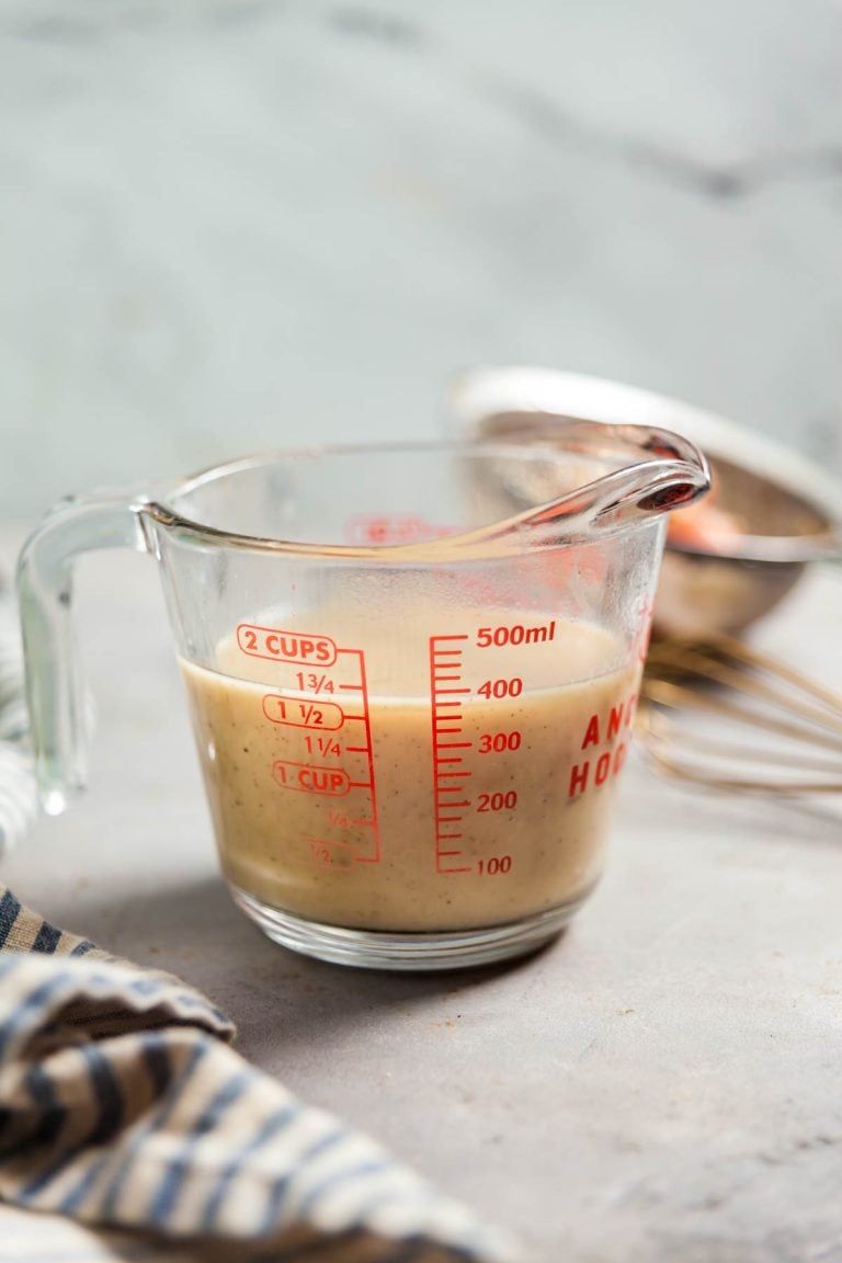 A measuring cup filled with chicken gravy. 