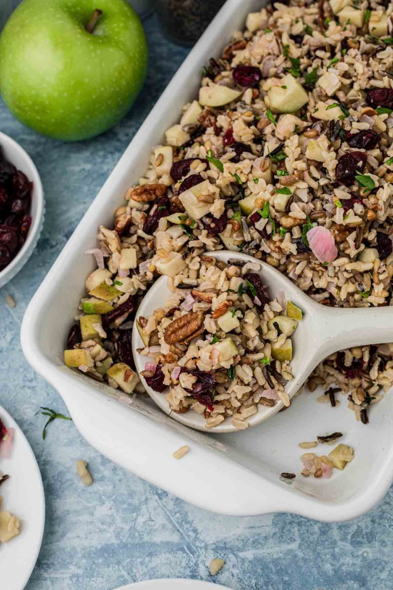 A white serving dish of apple and cranberry pilaf. 