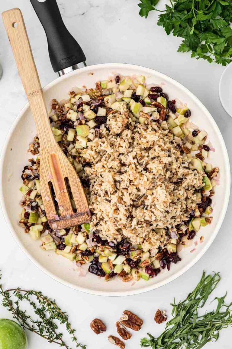 Adding brown rice to the pan of pilaf. 