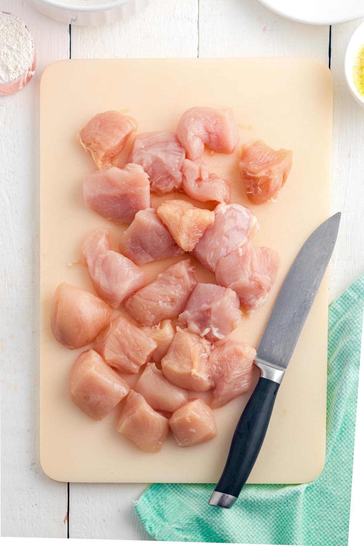 An overhead image of cutting the chicken into bite-sized nuggets ready to be breaded and fried.