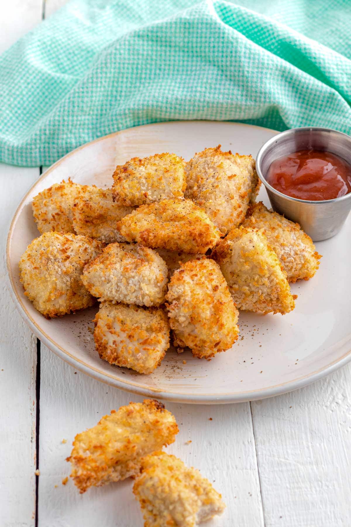 A plate of air fryer chicken nuggets with a cup of barbecue sauce on a white plate. 