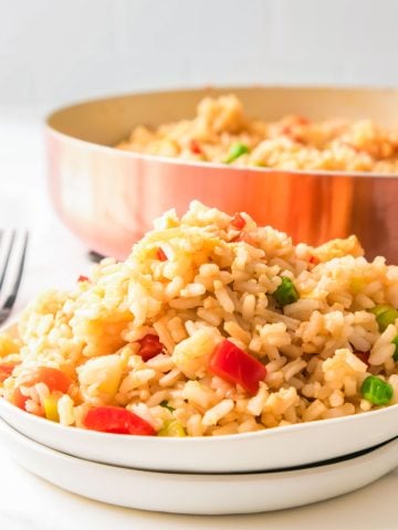 A big plate full of homemade fried rice, with a copper pot of fried rice in the background.