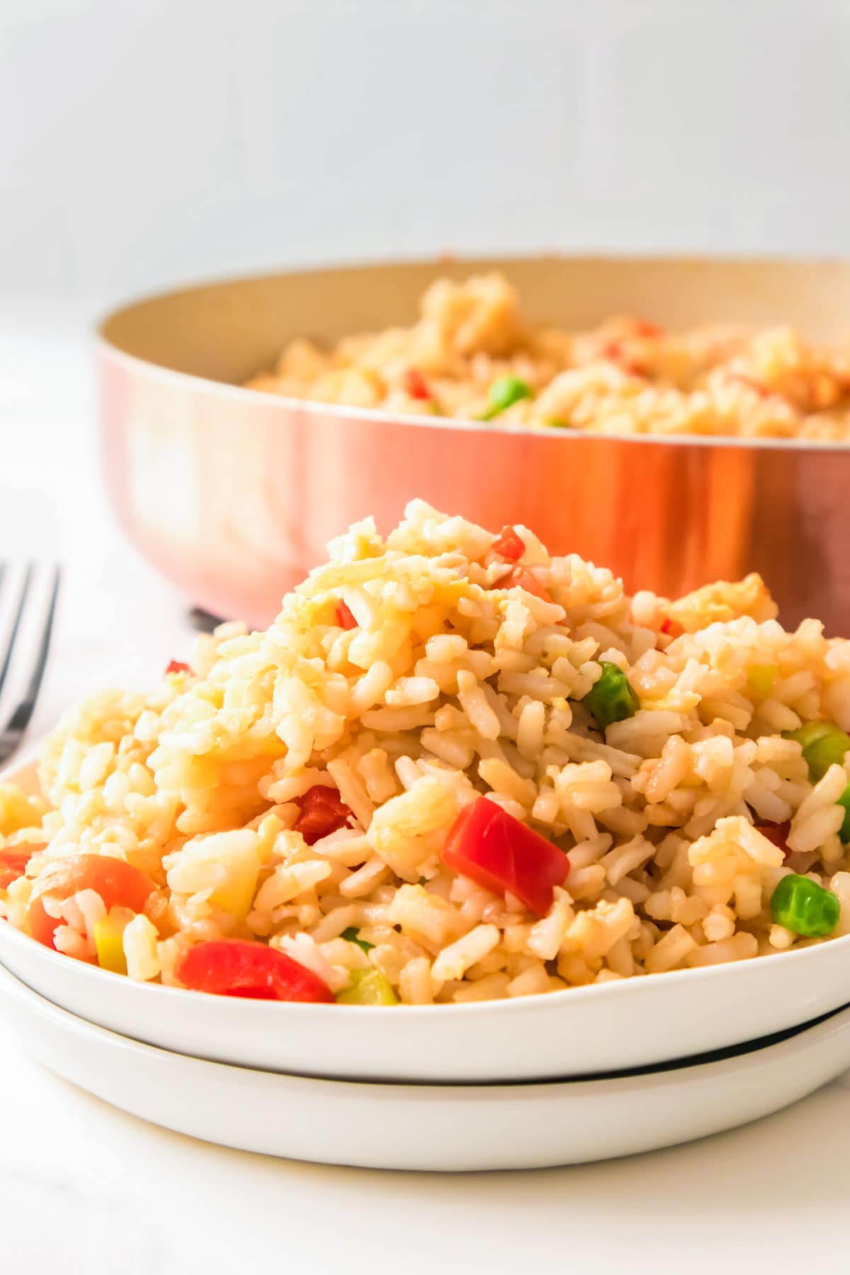 Once you know how to make fried rice, it's so easy! A big plate full of homemade fried rice, with a copper pot of fried rice in the background.