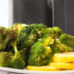 Garlicky roast broccoli in front of an air fryer.
