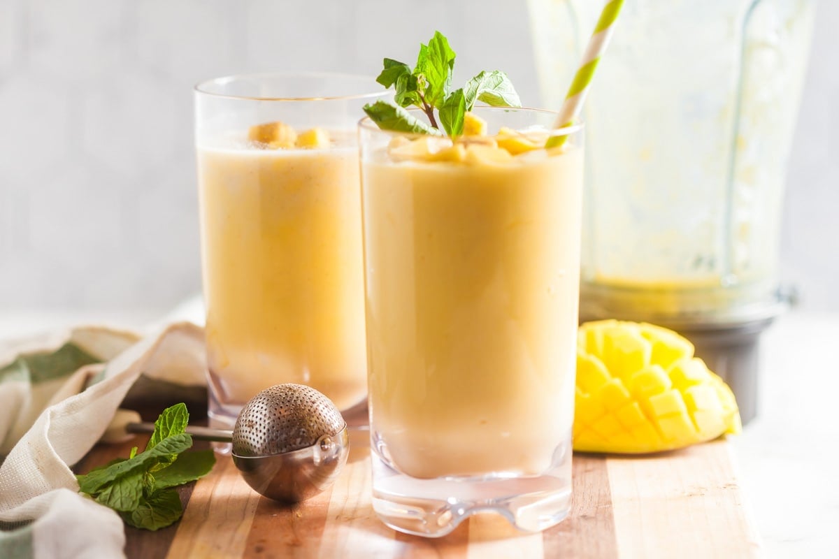 Landscapr view of two mango smoothies on a counter. 