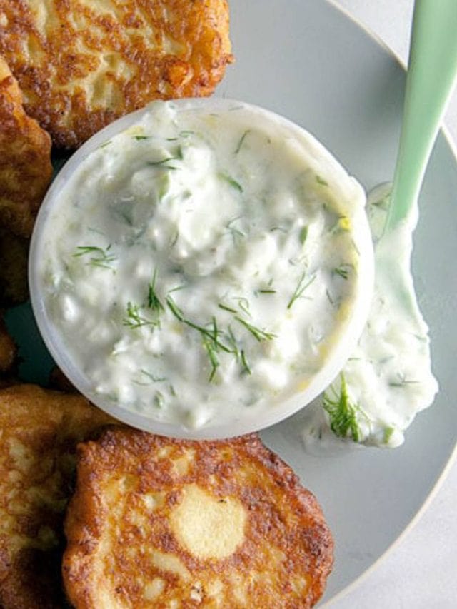 A dish of tzatziki sauce with zucchini fritters.