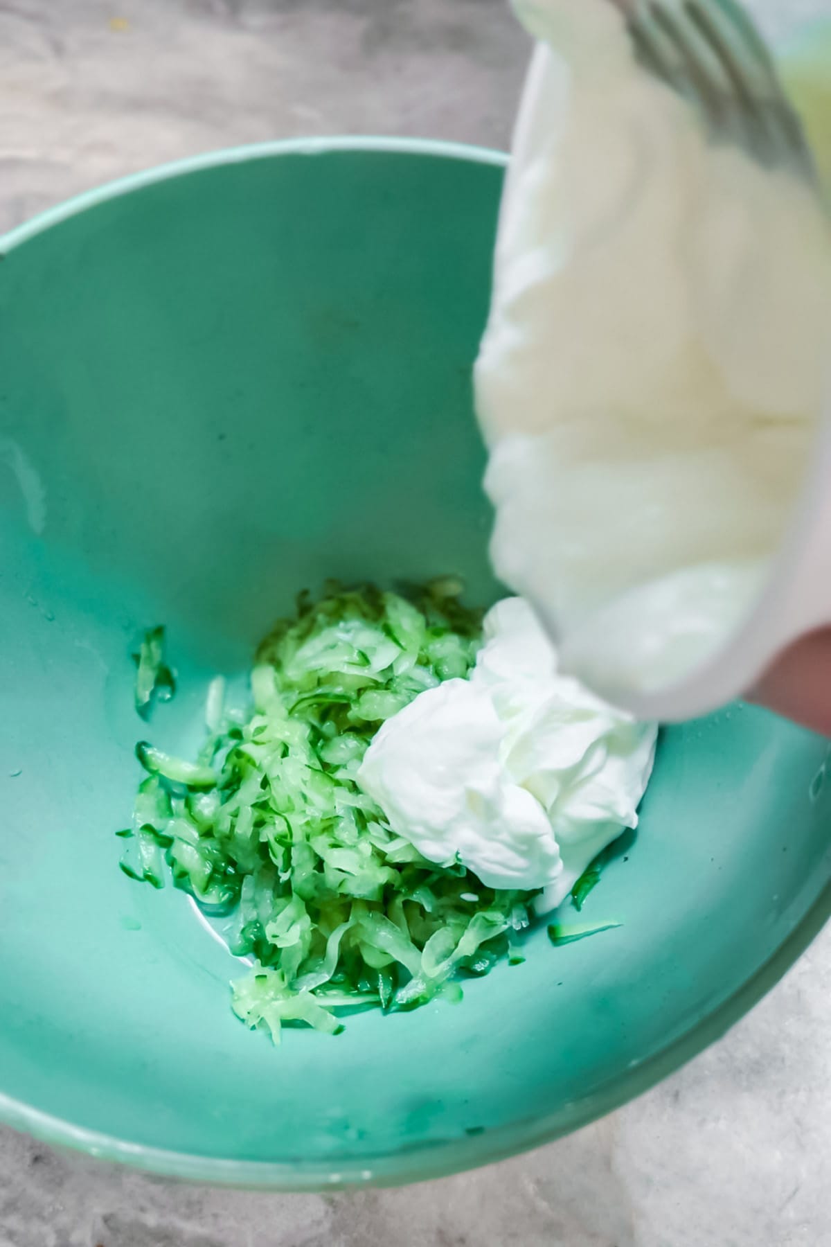 Step by step photos of how to make tzatziki sauce: Adding the yogurt to the cucumber. 