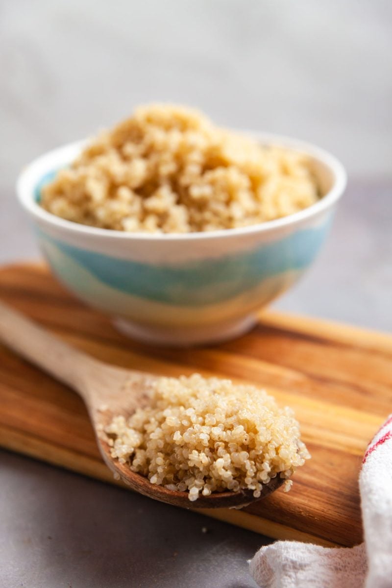 A bowl of cooked quinoa with a serving spoon. 
