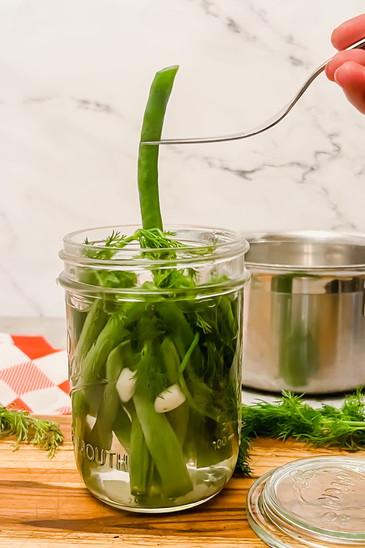 Using a fork to lift a dilly bean from the jar. 