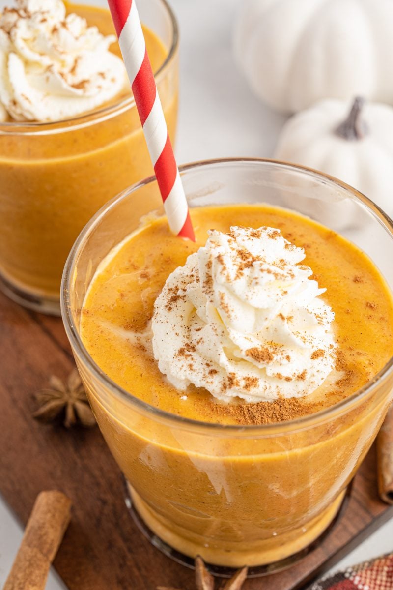 Closeup image of a pumpkin smoothie topped with whipped cream and pumpkin pie spice. 