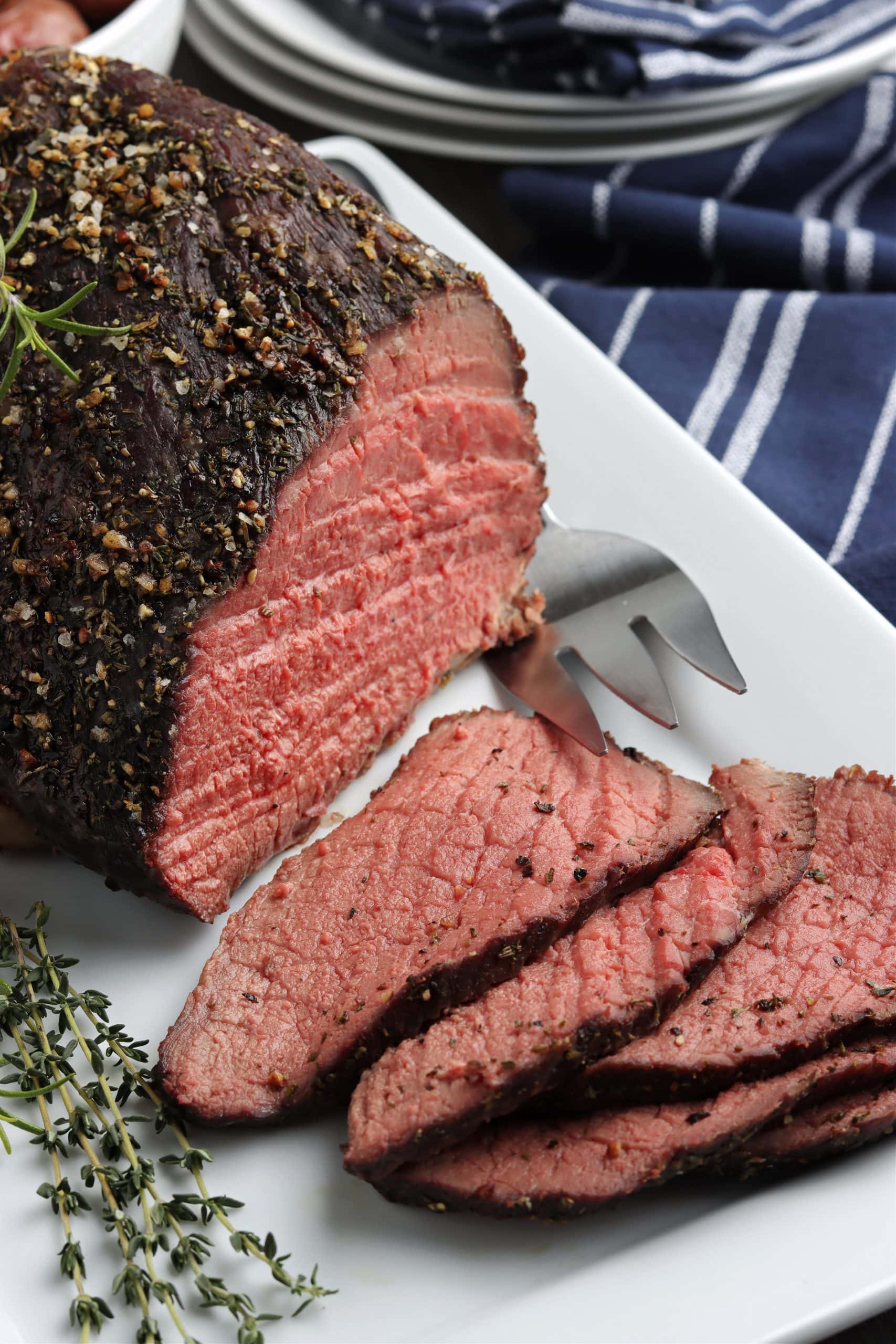 Thinly sliced rump roast beef on a white serving platter. 