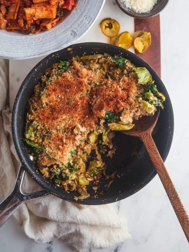 Overhead view of a skillet filled with Utica greens with a scoop being taken out.