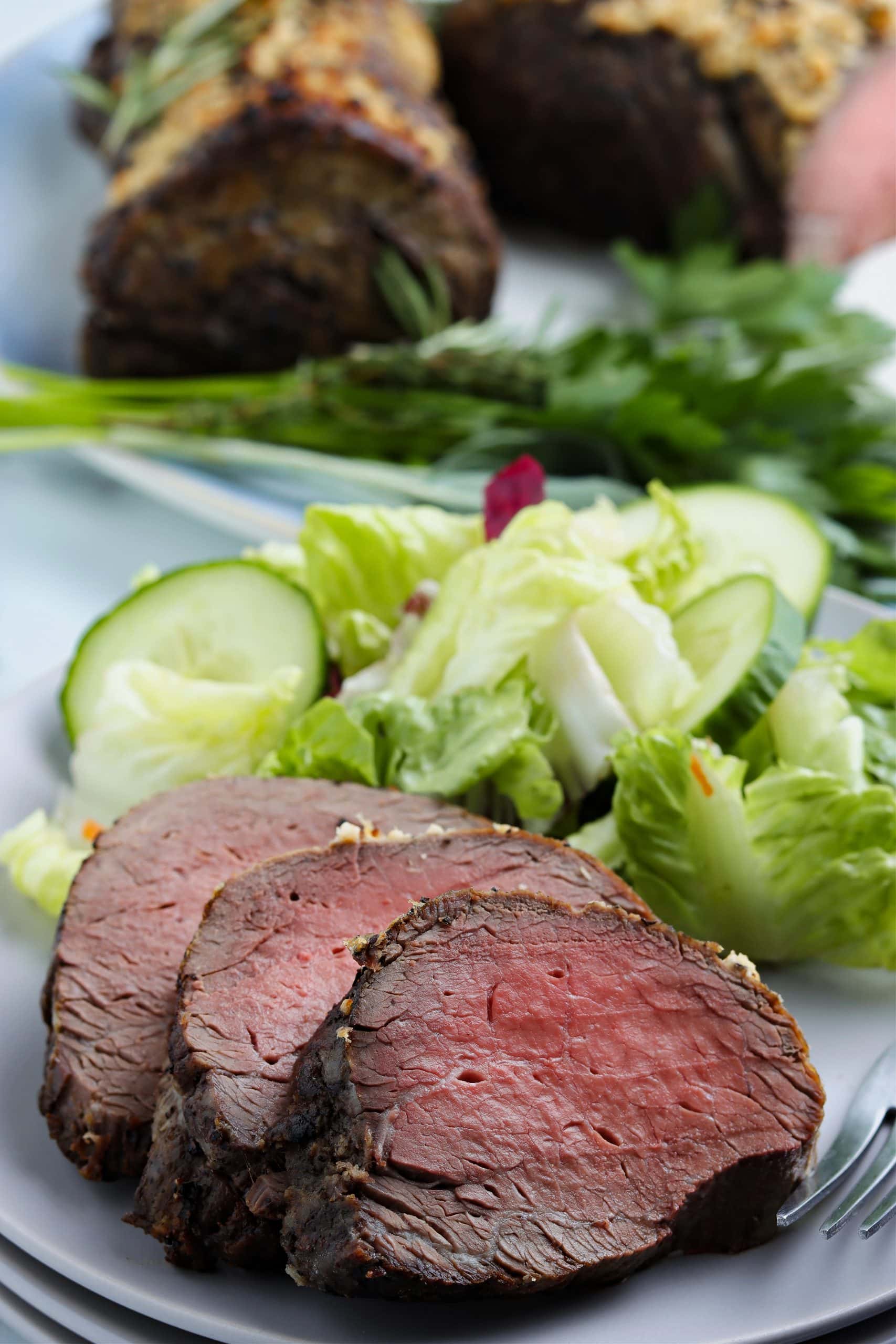 Horseradish crusted beef loin plated with a green salad. 