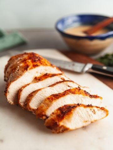 Juicy air fryer chicken breast, sliced on a white cutting board.