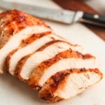 Juicy air fryer chicken breast, sliced on a white cutting board.