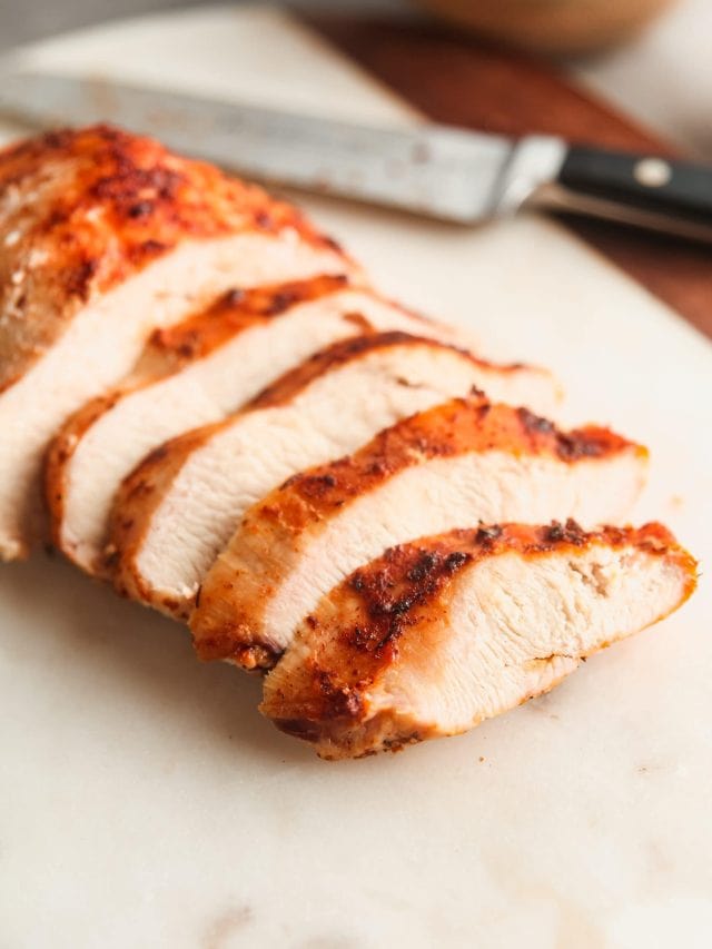 Juicy air fryer chicken breast, sliced on a white cutting board.