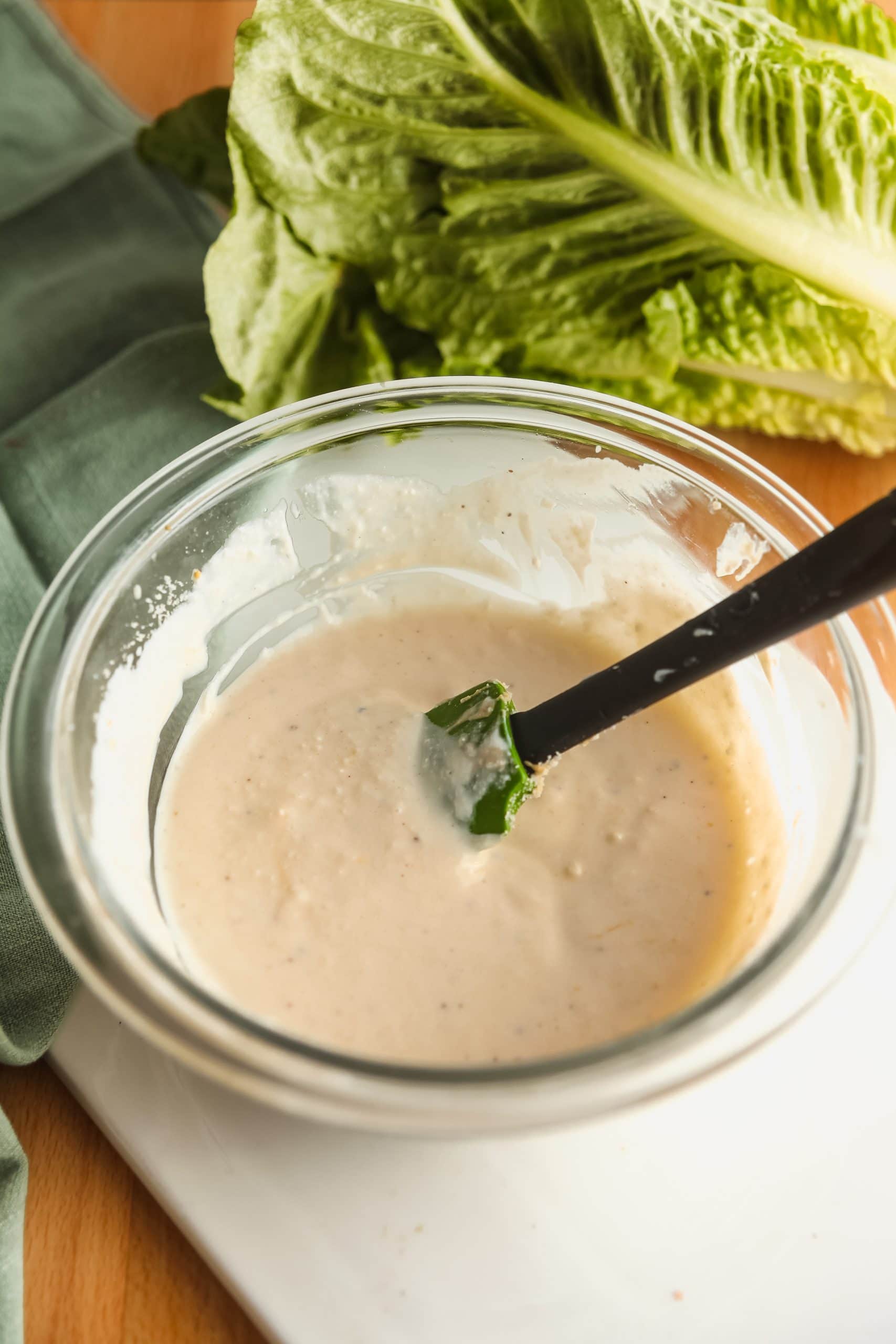 Mixing the homemade Caesar dressing in a glass mixing bowl.