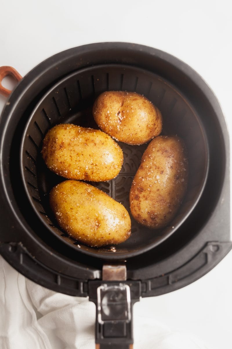 Raw potatoes in an air fryer basket.