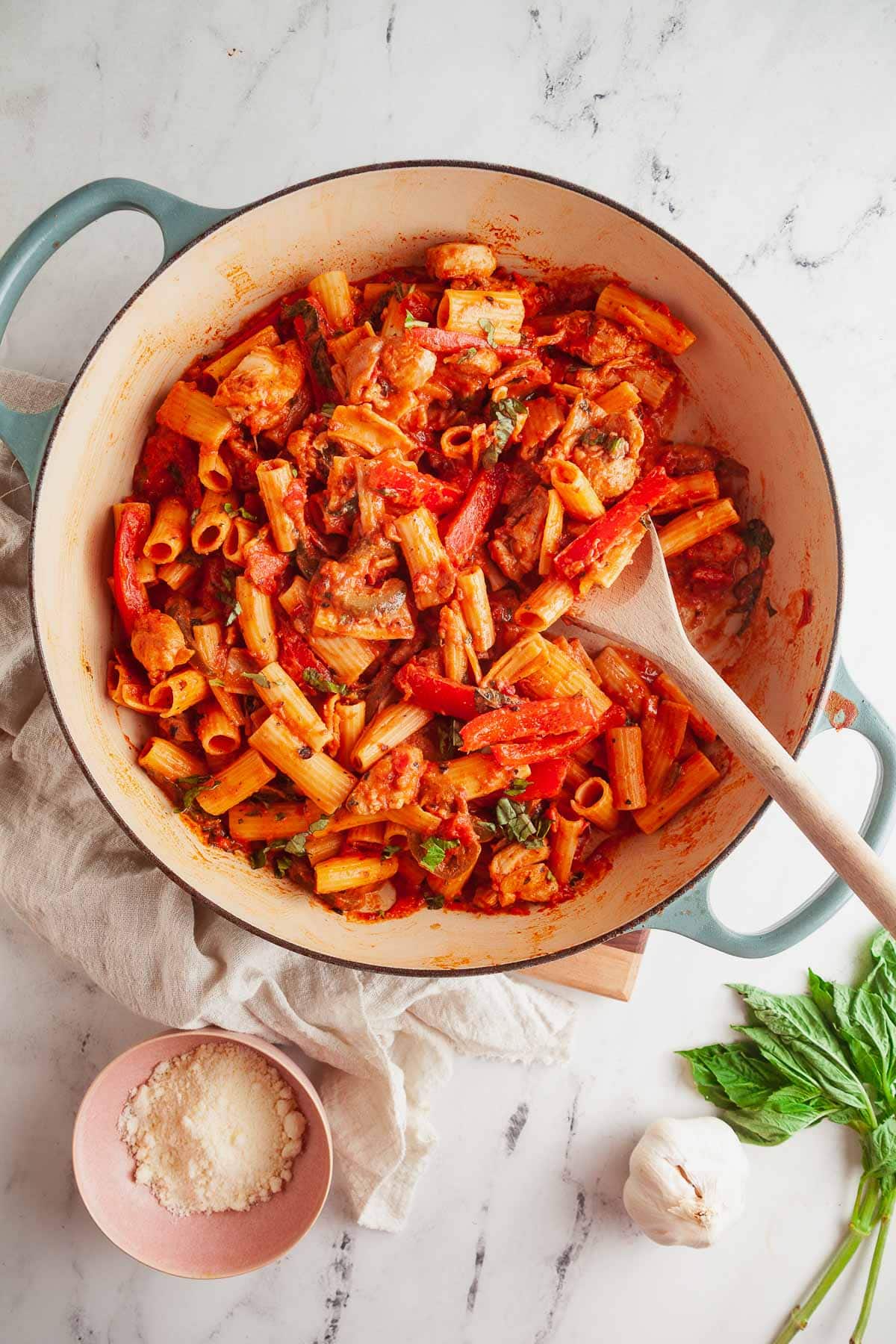 A pan of spicy chicken riggies with a wooden spoon, ready for serving. 